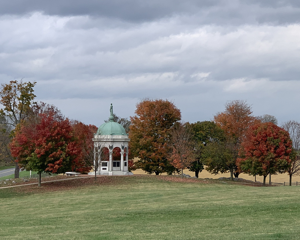 green dome on top of 8 sided monument, red and yellow leaf trees, grass in foreground