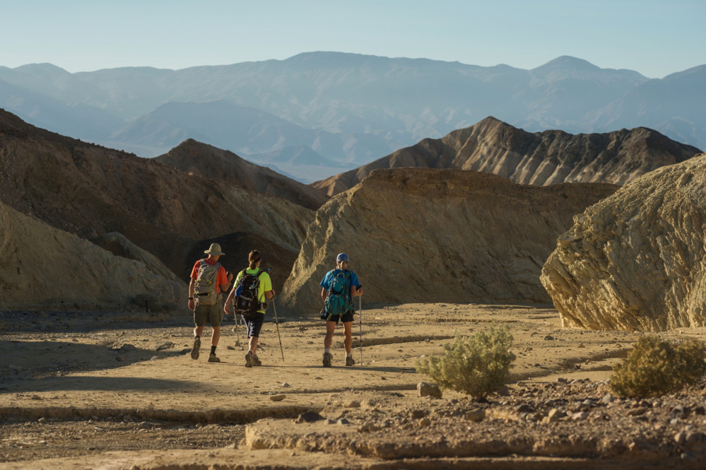 Three hikers walk away from the camera in Death Valley National Park.