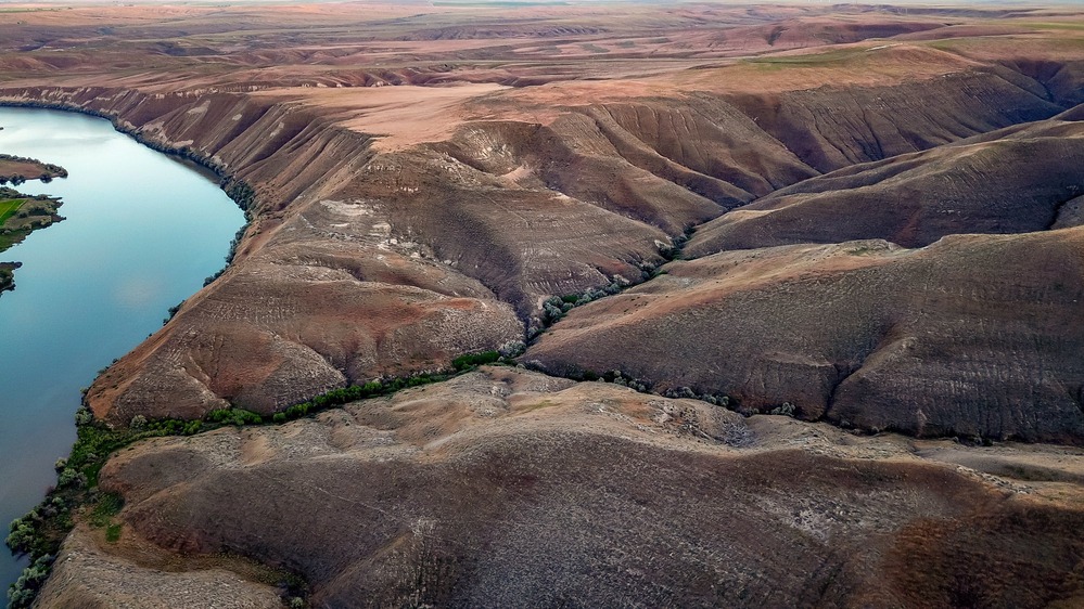 view of the fossil beds from a drone up high showing the folds of land and part of the Snake River