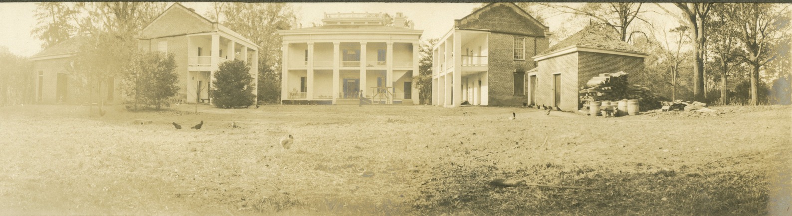 large mansion surrounded by four outbuilding forming a half square